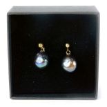 A pair of 9ct gold dark pearl studs, in a black blue/purple ground, on single pin backs with butterf