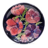 A Moorcroft Anemone pattern pottery charger, blue ground, impressed and painted marks, 35cm diameter