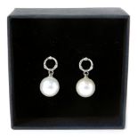 A pair of 9ct white gold pearl and diamond drop earrings, with a circle halo ring, set with three ti