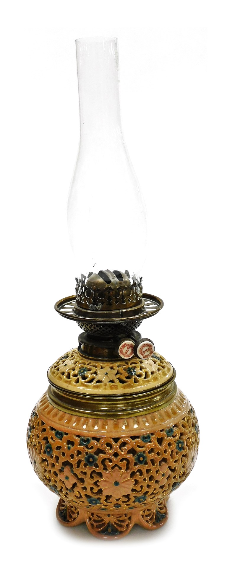 An early 20thC pottery oil lamp, with a clear glass chimney, the base with reticulated floral decora