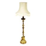 A turned brass standard lamp, with cream coloured shade with fringe borders, on a domed foot, 171cm