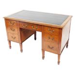 An Edwardian Sheraton revival inlaid mahogany kneehole desk, with inset green leather top, fitted wi