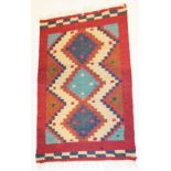 A Kilim red ground prayer rug, decorated with three central medallions, 99cm x 62cm.