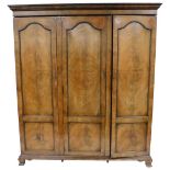 An early 20thC Georgian style mahogany triple wardrobe, the outswept pediment over three doors, encl