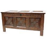A 17thC oak coffer, with later carved triple panelled front, raised on stile supports, 69cm high, 14