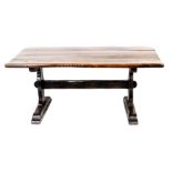 An oak and elm refectory table, the planked top with a rounded edge, on shaped trestle shaped end su