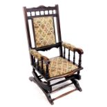 An early 20thC American rocking chair, with a stained frame, the padded back, arms and seat in tapes