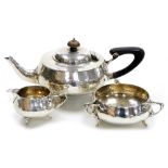 A George V Arts and Crafts style silver three piece tea set, with hammered decoration, comprising te