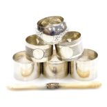 A group of six silver napkin rings, each of differing size, shape and decoration, together with a bu