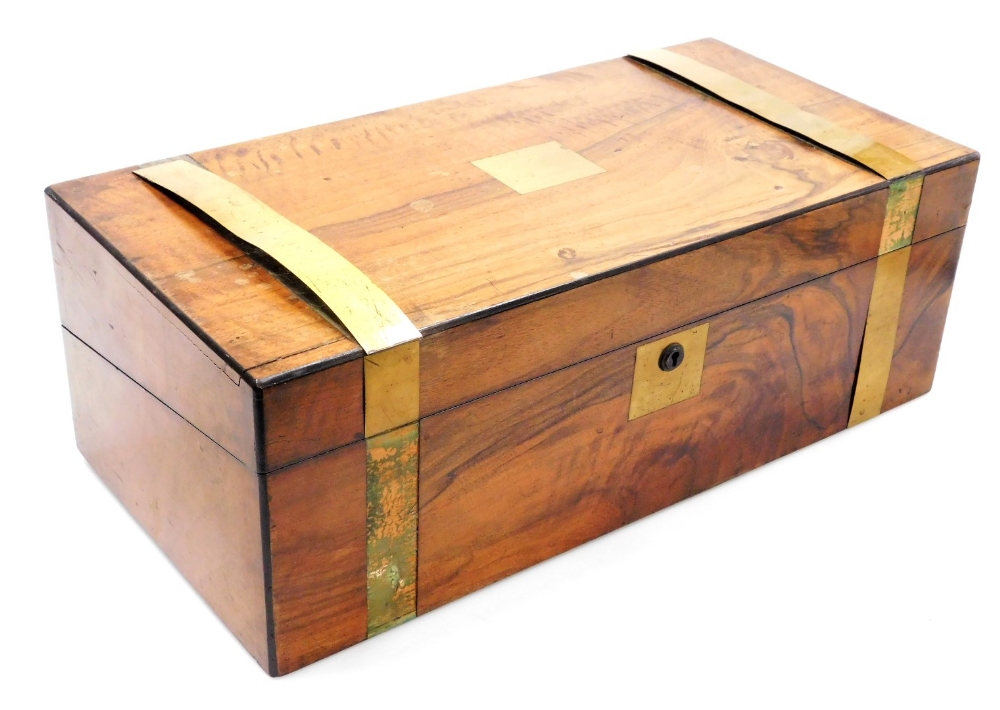 A Victorian walnut and brass bound writing slope, the hinged lid opening to reveal a red baize slope