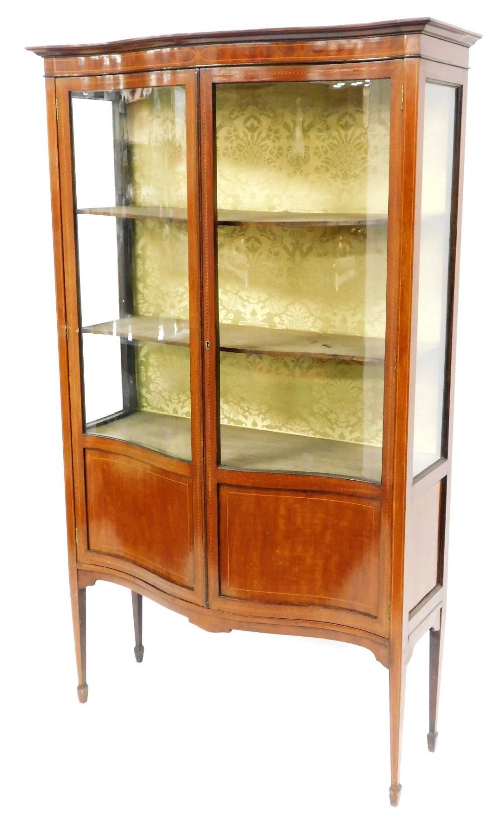 An Edwardian inlaid mahogany serpentine fronted display cabinet, with three shaped shelves and silk