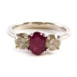 An 18ct white gold trilogy ring, set with an oval ruby approx. 1.10ct flanked by two round brilliant