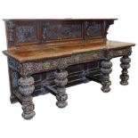 A Victorian oak breakfront sideboard, the shelf topped panelled back carved with masks, fruit and fl