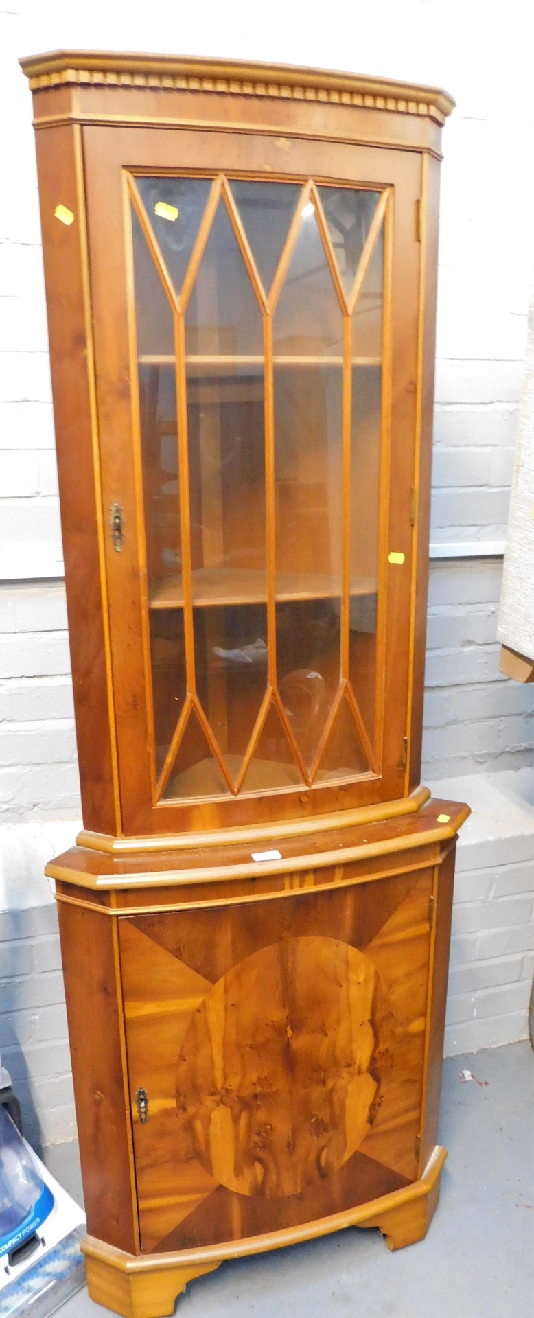 A reproduction yew standing corner cabinet, the top with a moulded dental cornice, the hinged door w