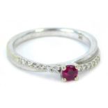 A 9ct white gold dress ring, of twist design, set with tiny diamonds and central garnet, ring size M