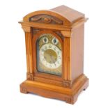 An early 20thC Junghans oak cased mantel clock, the arched brass dial with foliate scroll spandrels,
