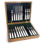 A part canteen of mother of pearl and stainless steel bladed fruit knives and forks, in a fitted oak