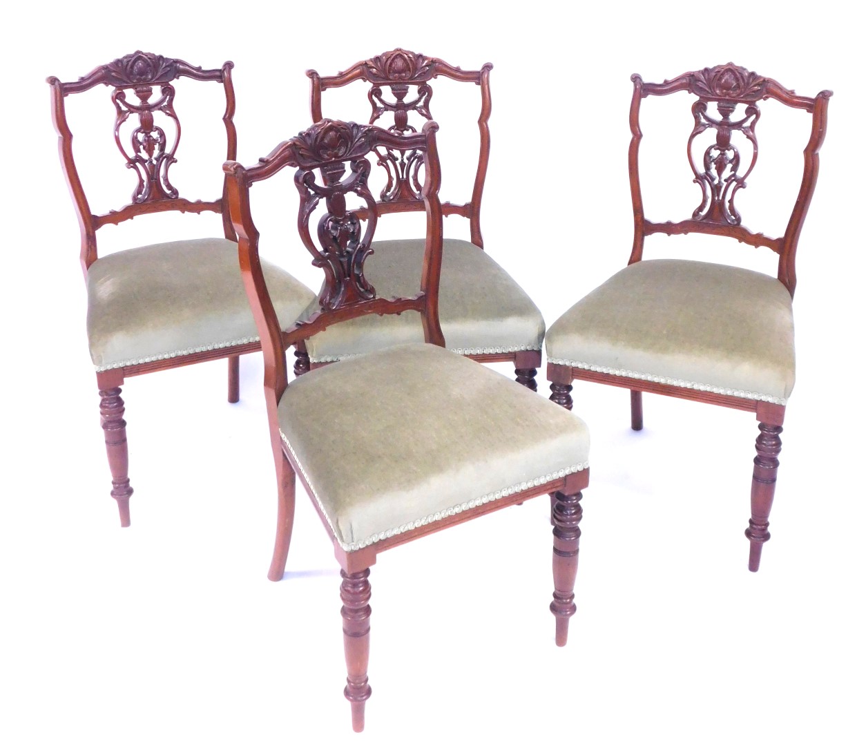 A set of four Victorian walnut single dining chairs, each with a carved and flared back, on turned l