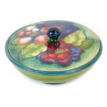 A Moorcroft pottery Clematis pattern bowl and cover, with a transitional blue to green ground, signe