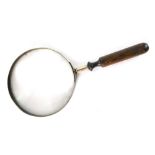An early 20thC magnifying glass of large proportion, with turned handle, 33cm high.