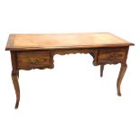 A French walnut writing table, the rectangular top with a brown tooled leather inset, above two frie