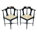 A pair of Edwardian corner chairs, each upholstered in buttoned material, with scroll arms and inver