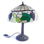 A Tiffany style table lamp, the glass shade set with leaves and berries, 43cm diameter.