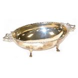 An Edward VII silver two handled dish, of oval form, with a raised border and pierced bow shaped han