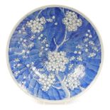 A Japanese blue and white porcelain charger, decorated with prunus blossom against a scale ground, r