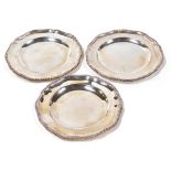 Three Edwardian silver dinner plates by R & S Garrard & Co, of Georgian design, with scalloped and g
