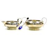 A George V silver two handled sugar bowl and matching cream jug, each of squat rounded form with rib