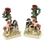 A pair of Staffordshire style pottery spill vases, in the form of a boy and girl seated beside dogs