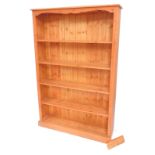 A pine open bookcase of five shelves, raised on a plinth base, 182cm high, 122cm wide, 29cm deep.