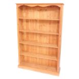 A pine open bookcase of five shelves, raised on a plinth base, 182cm high, 122cm wide, 29cm deep.