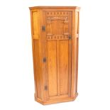 An early 20thC oak hall robe, with a carved panelled door, opening to reveal hanging hooks and a glo
