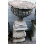 A reconstituted stone garden urn, semi fluted circular form, on a square base, on shaped plinth, 84c