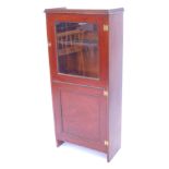 An early 20thC mahogany and oak cupboard bookcase, the glazed and panelled door opening to reveal sh