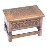An early 20thC oak sewing box, with a carved fret and arch front, raised on turned and square legs u