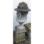 A reconstituted stone garden urn, with fruits and flowers top, of campana form with relief moulded f