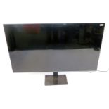 A Philips 65" flat screen television, model 65PUS7906-12, serial no FZ2A2138045495, on a black glass