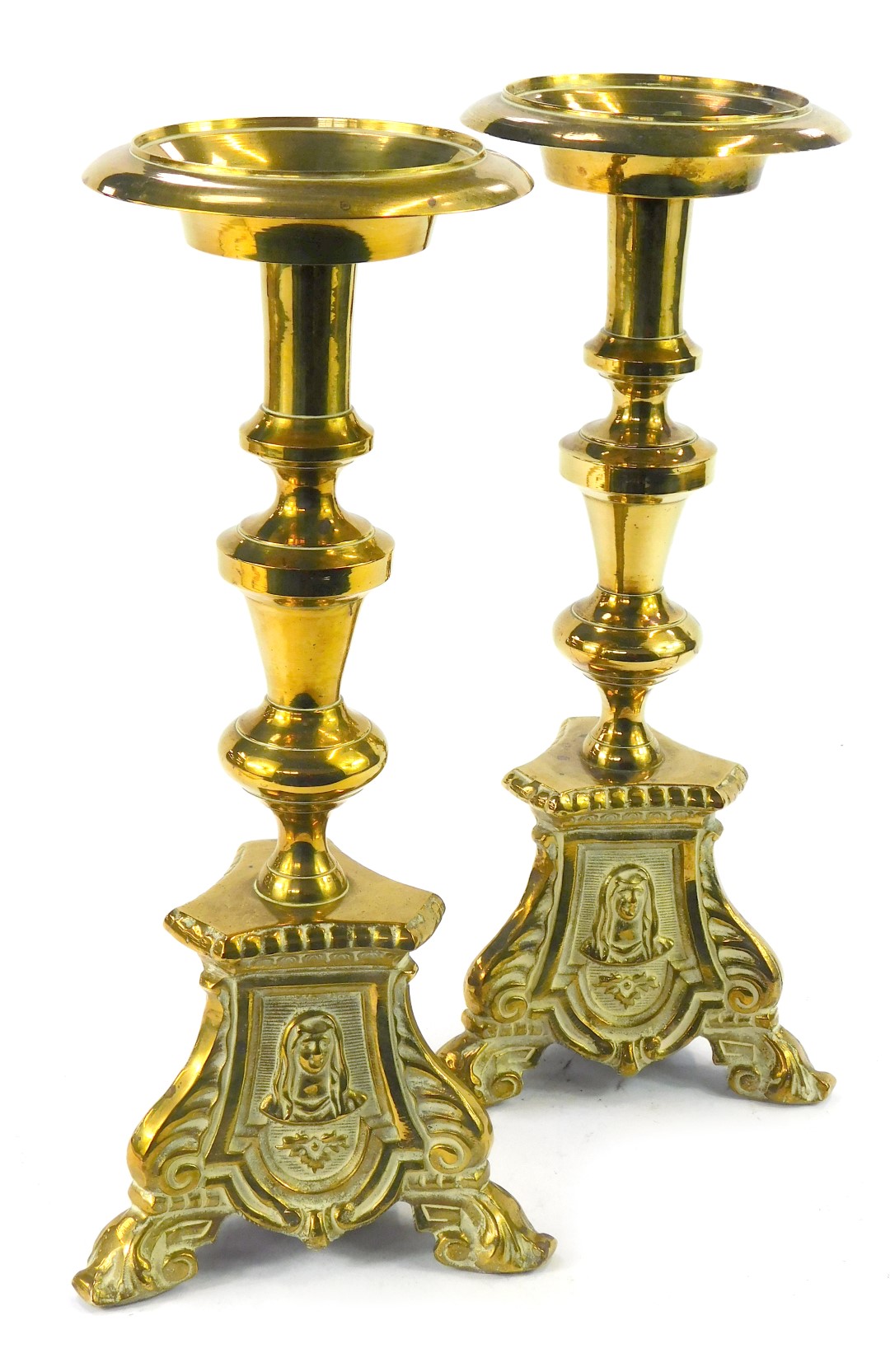 A pair of early 20thC brass pricket altar candlesticks, each on a tripod base, embossed with the hea