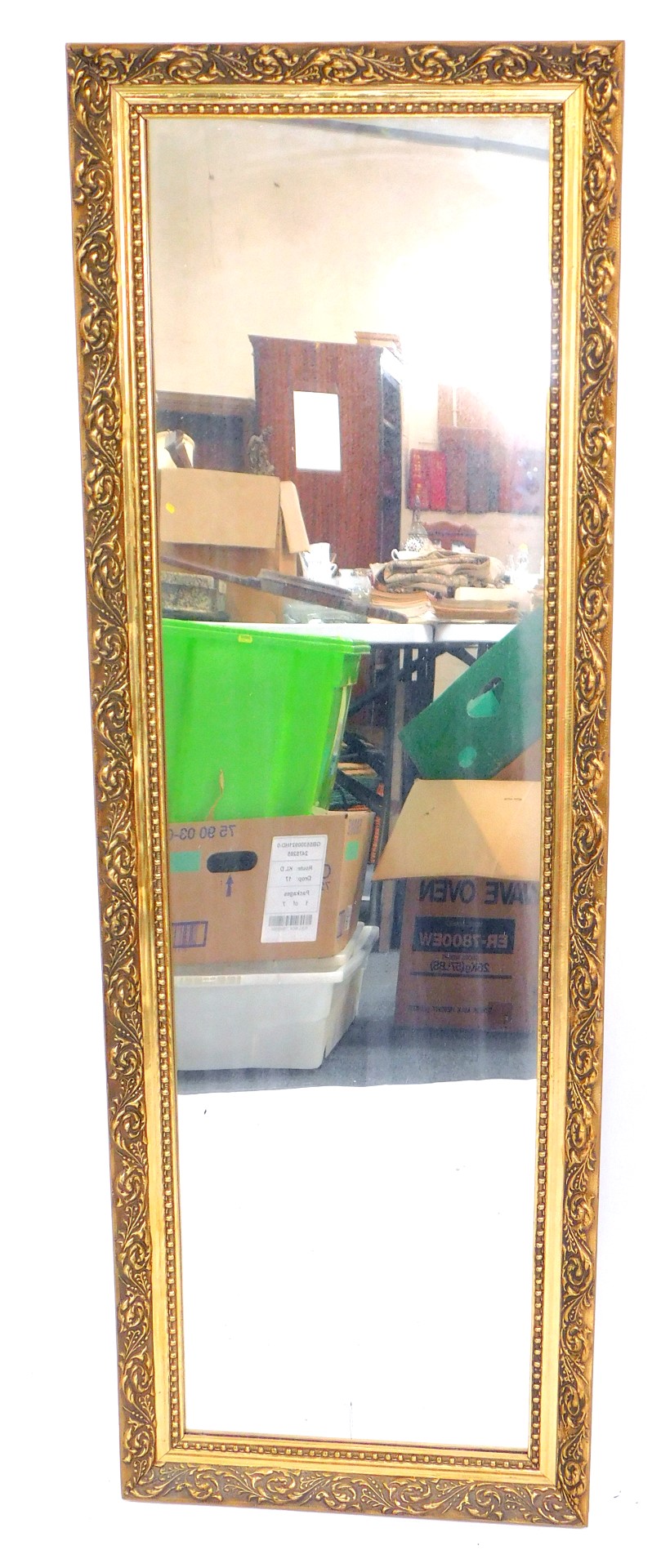 A rectangular gilt framed wall mirror, decorated with foliate scrolls, 113cm x 37.5cm.