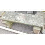 A stone garden bench, formed as heavy plinth on two supports, 40cm high, 114cm wide.