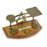 A set of 19thC brass letter scales, with weights, on an oak base, 10cm high, 20cm wide, 11cm deep.