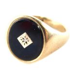 A 9ct gold signet ring, with oval signet, set with jet and a central tiny diamond, on a plain band,