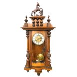 An early 20thC walnut Vienna wall clock, with heavily carved horse finial flanked by urns, above a 1