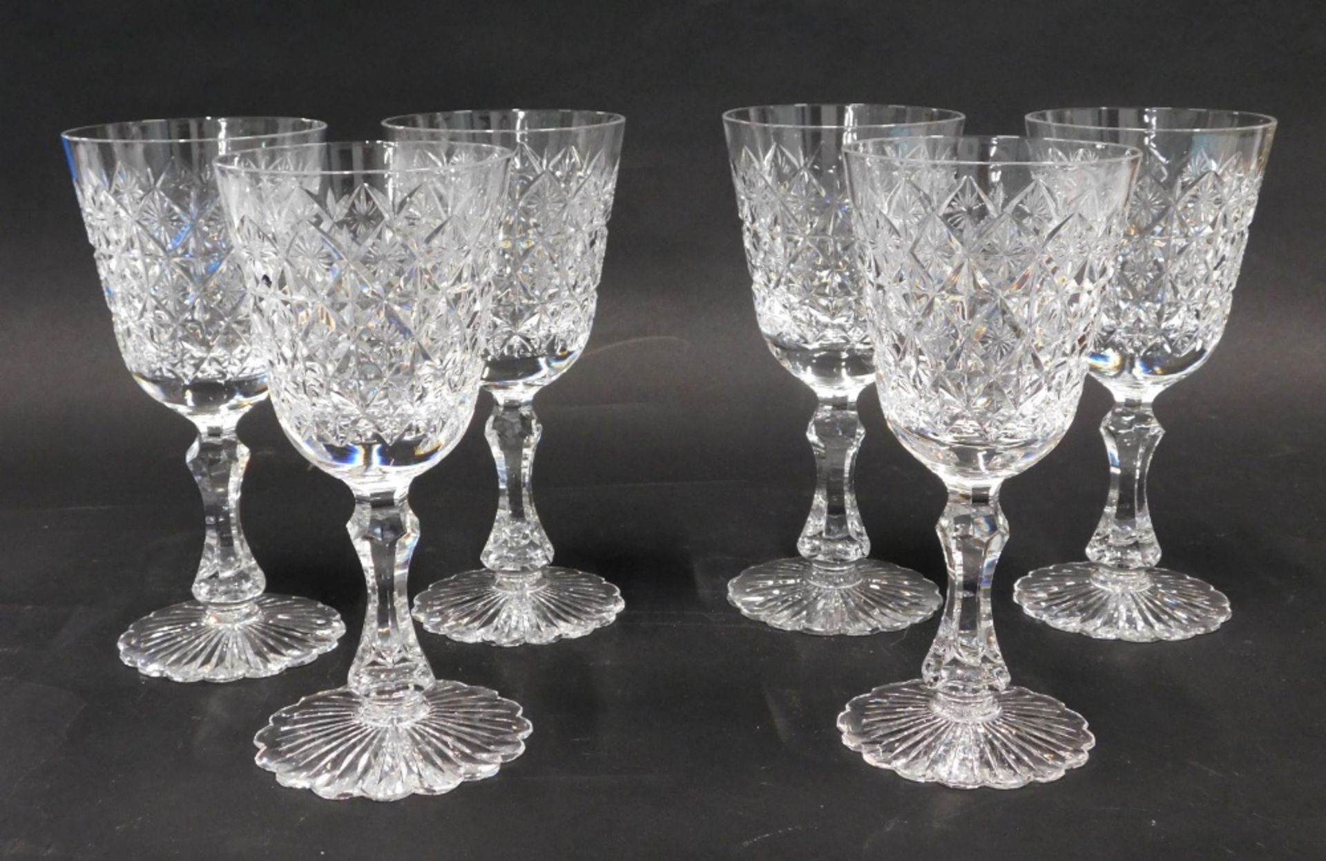 A set of six heavy crystal wine glasses, with a repeat hobnail cut diamond decoration, on shaped ste