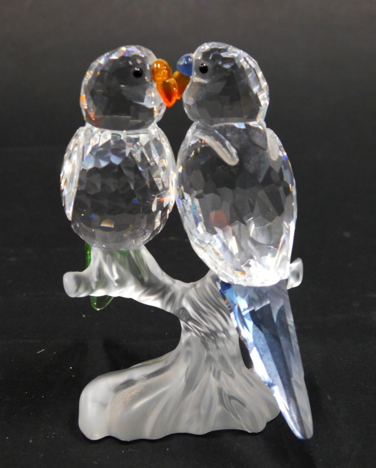 A Swarovski Crystal figure group of lovebirds, in clear, frosted, orange, blue and black glass, swan