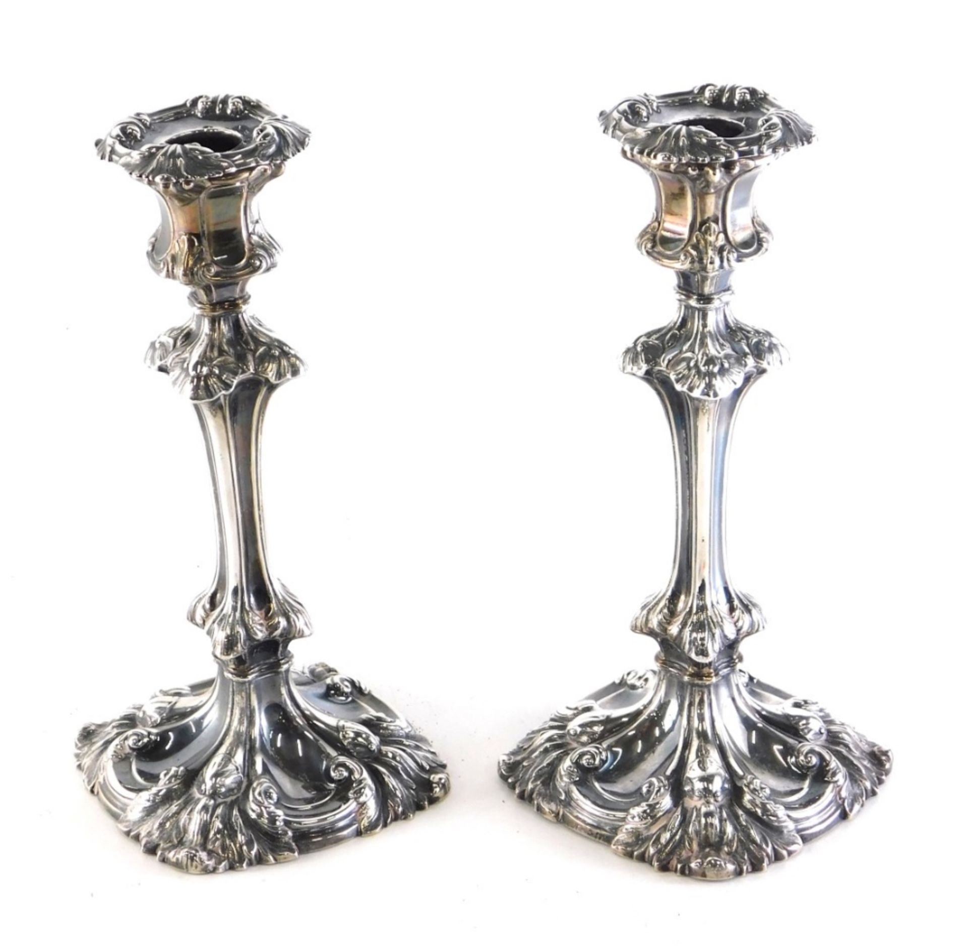 A harlequin pair of William IV candlesticks, by Henry Wilkinson & Co, each repousse decorated with l