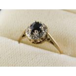 A 9ct gold cluster ring, set with oval sapphire in six claw setting, surrounded by six tiny diamonds